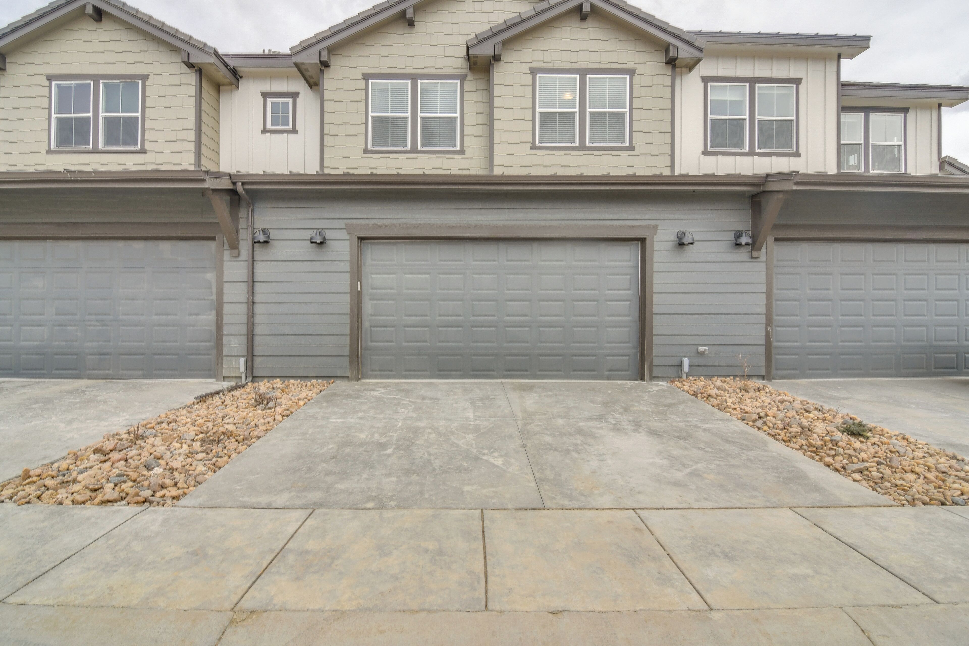 Une maison à deux étages avec un garage, une allée et un chemin en pierre.