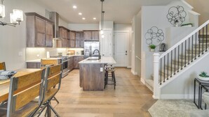 Une cuisine moderne avec des meubles en bois, un îlot central et un coin repas doté de chaises en métal.