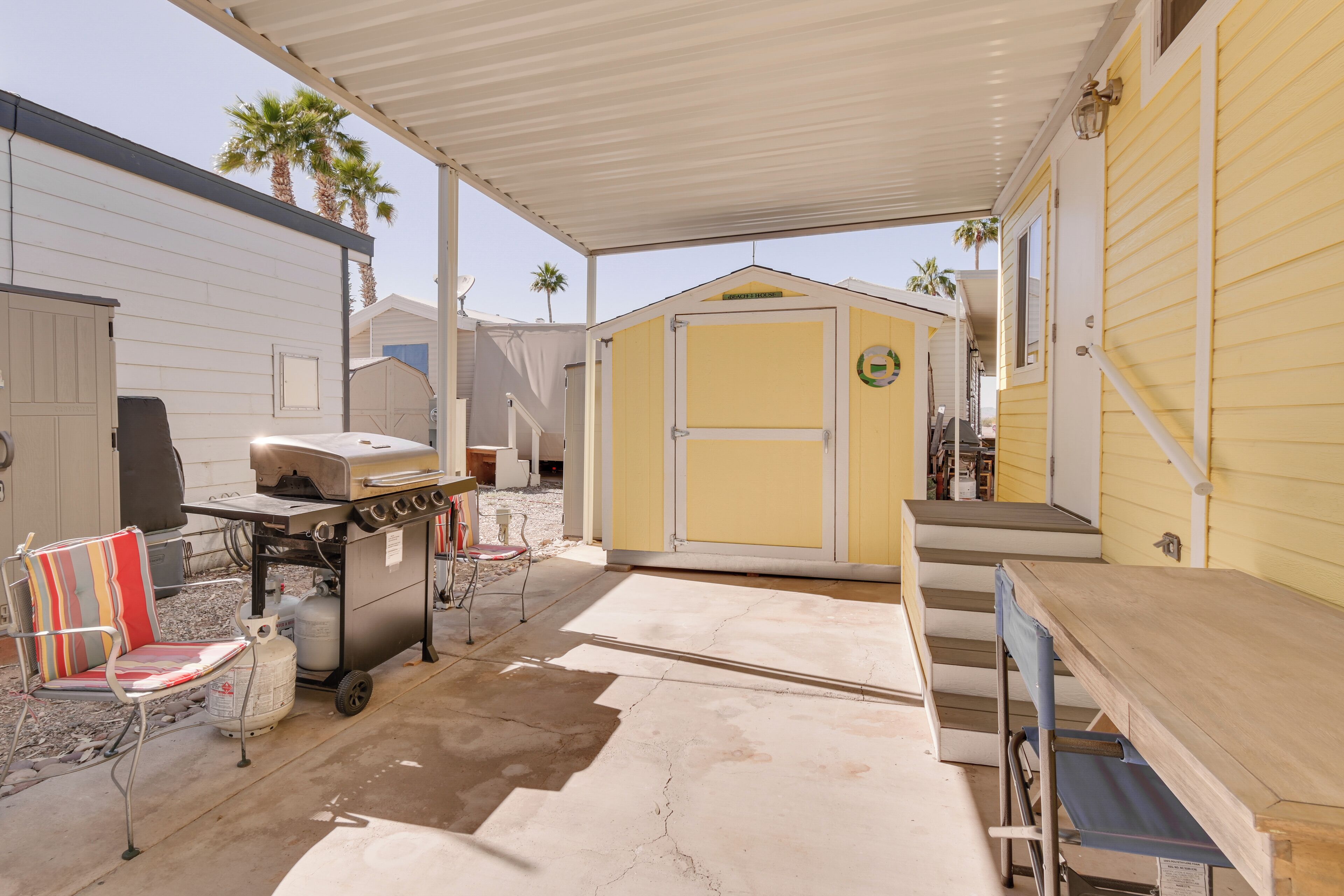 A covered patio area with a grill, a chair, and a table.