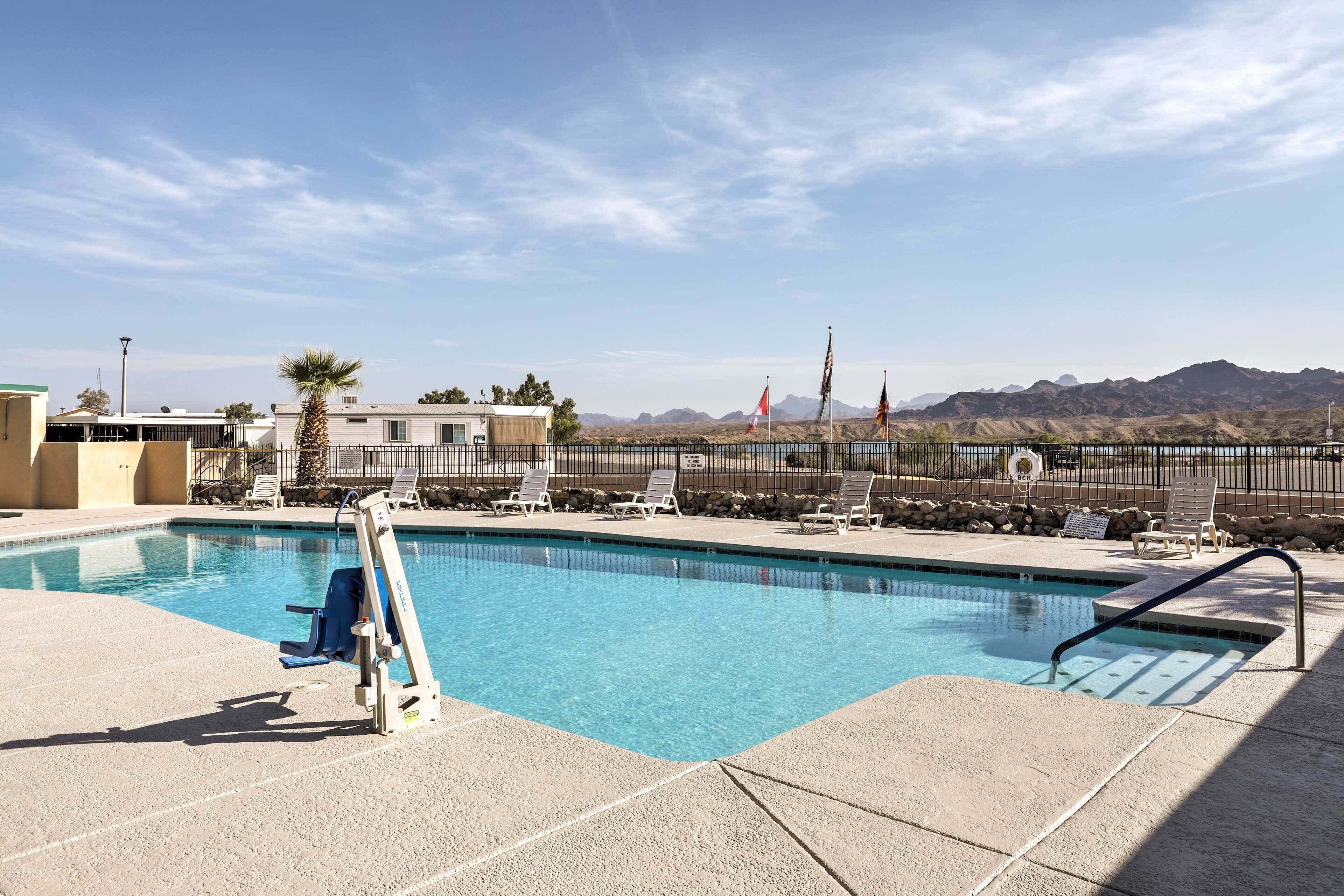 A swimming pool with clear blue water, surrounded by lounge chairs and a lifeguard stand.