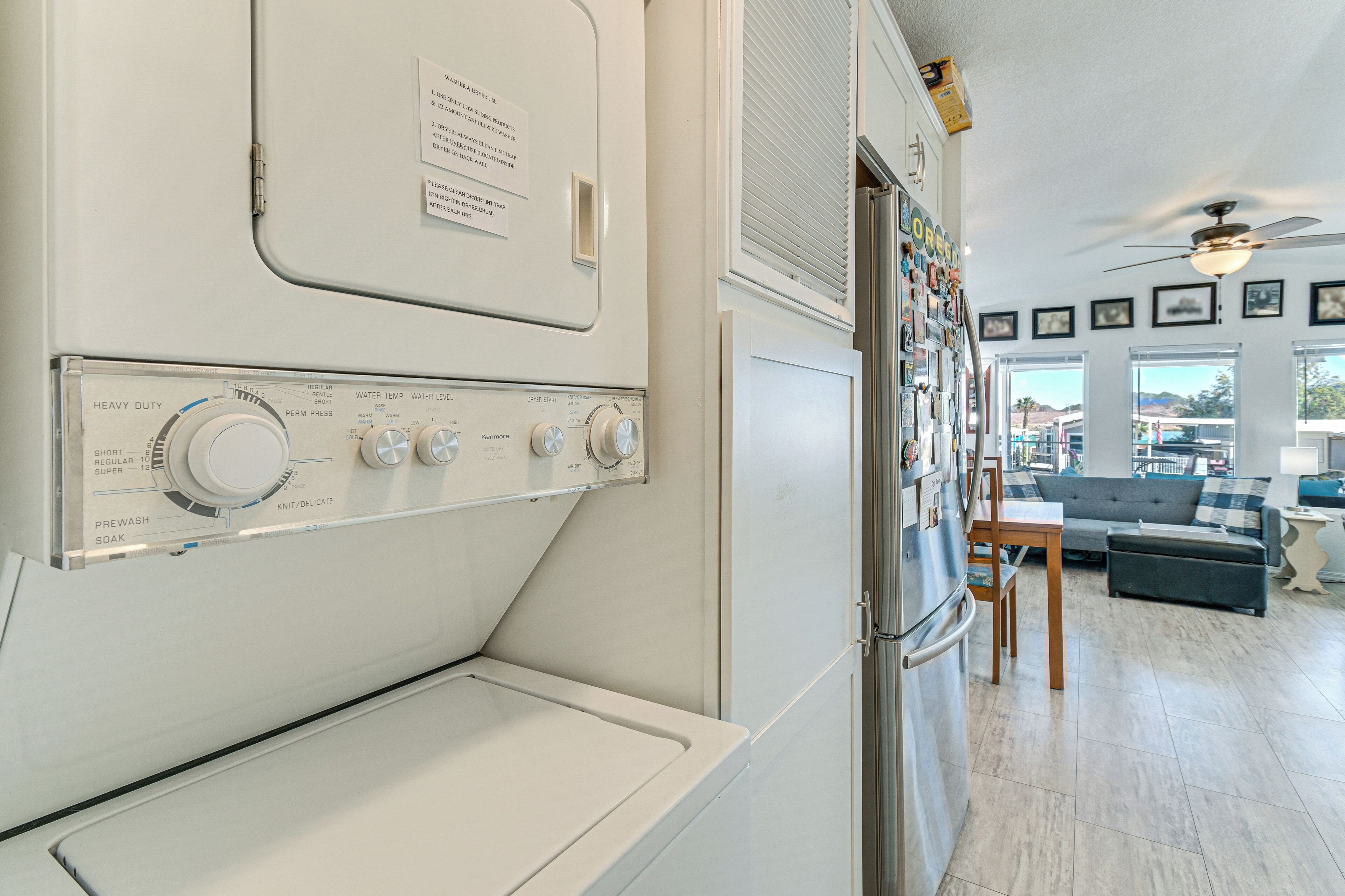 A laundry room with stacked washers and dryers, a ceiling fan, and a view of the outside through large windows.