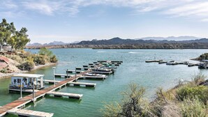 A marina with docked boats, a small building with palm trees, and mountains in the background. - Steps to Beach: Lake Havasu City Home w/ Grill! (Lake Havasu City)