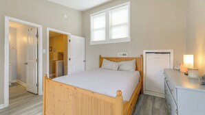 Een slaapkamer met een houten bed, een dressoir, een bureau en een raam.