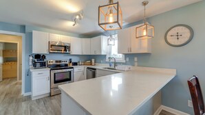 Een moderne keuken met witte kasten, roestvrijstalen apparatuur en hanglampen.