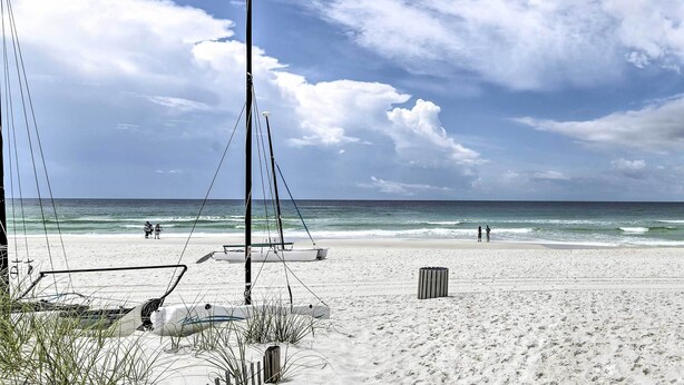 Ein Strand mit Segelboot, Laterne und Mülleimer.