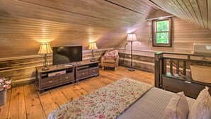 Un dormitorio acogedor con paredes de madera, una cama con ropa de cama floral, un televisor y dos lámparas.