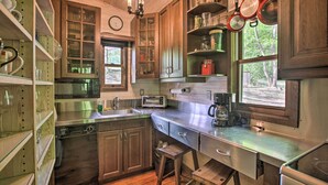 Una cocina con armarios de madera, electrodomésticos de acero inoxidable y una ventana con vistas a árboles.