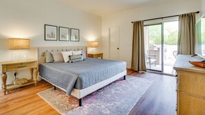 Une chambre à coucher avec un lit, des tables de chevet, un bureau et une vue sur l’extérieur.