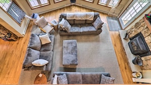A spacious living room with a gray sectional sofa, ottomans, and a stone fireplace. - Riverview Big Bass Lake Poconos Retreat (Gouldsboro)