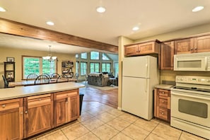 A spacious kitchen with wooden cabinets, a large island, a refrigerator, and an oven.
