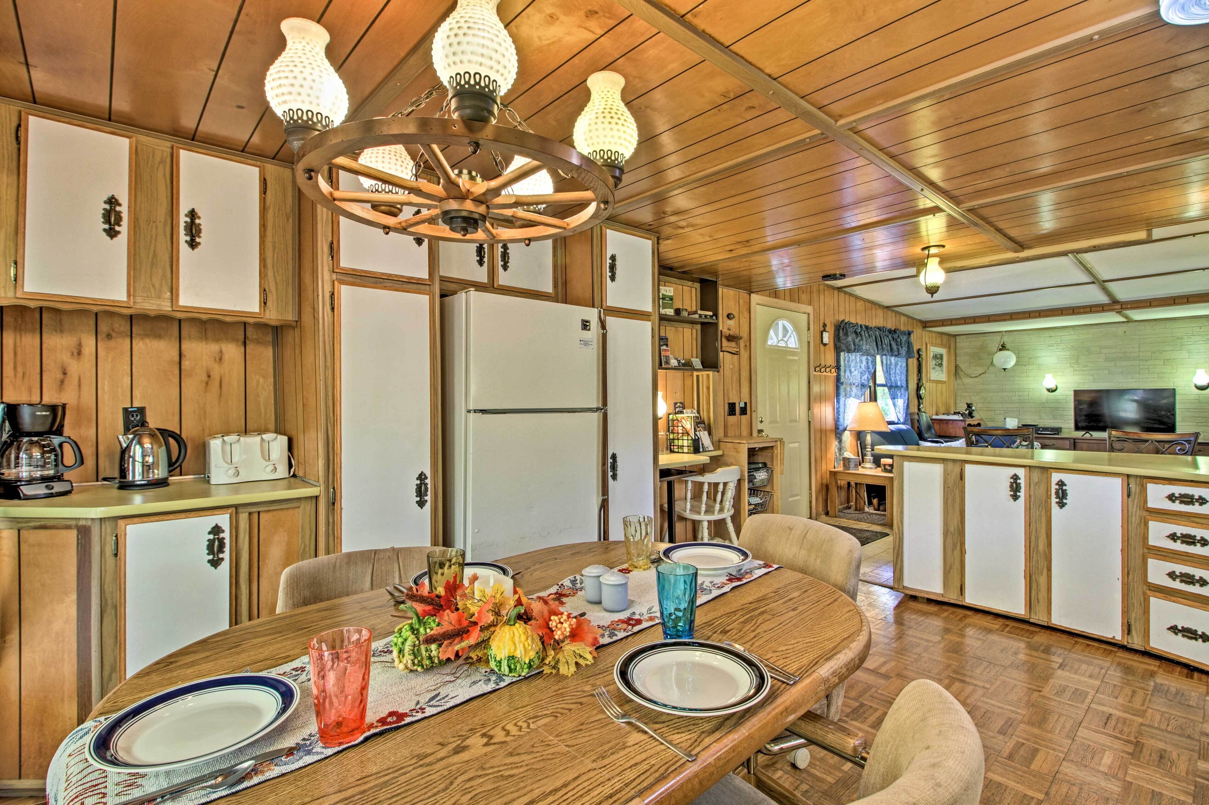Un intérieur en bois comprenant une table à manger pour deux personnes, un coin cuisine et un téléviseur.