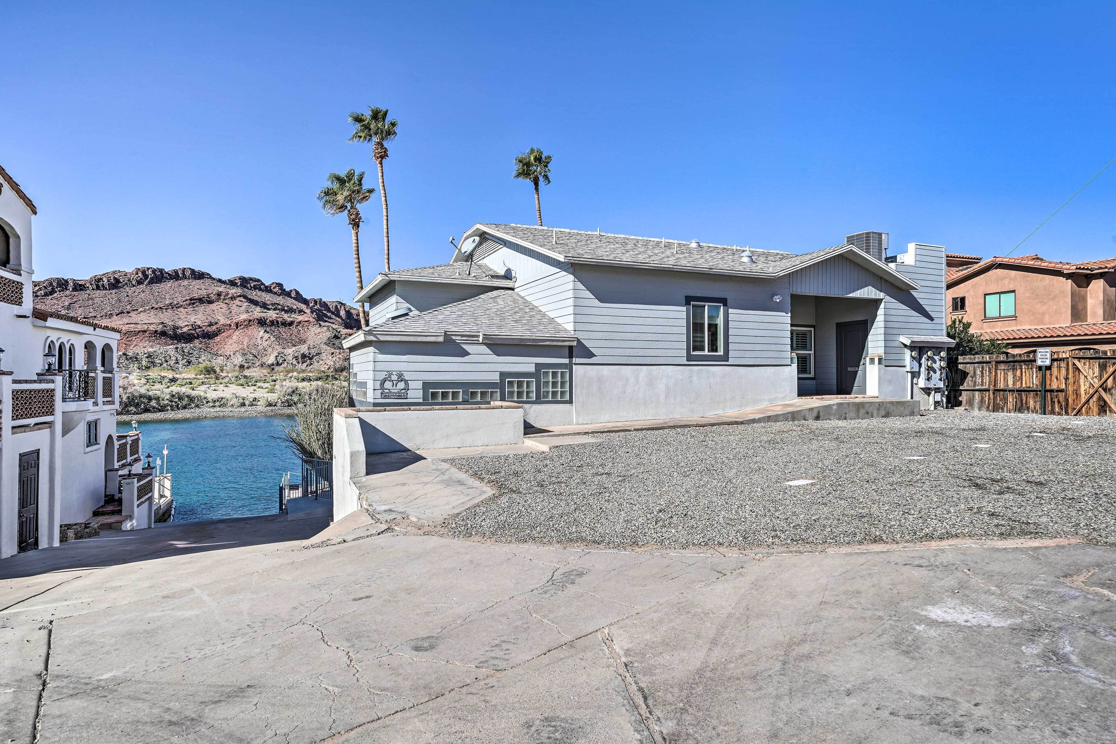 A residential property with a swimming pool, a paved driveway, and a rocky hillside in the background.
