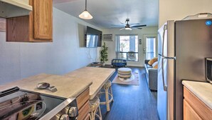 A modern kitchen with a built-in stove, bar stools, a ceiling fan, and a refrigerator. - Parker Studio w/ Patio & Direct River Access! (Parker)