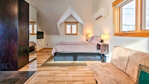 A bedroom with a loft-style ceiling, a bed, a sofa, a TV, and a window with a view. - Updated Boulder Studio ~ 1 Mi to Pearl Street (Boulder)
