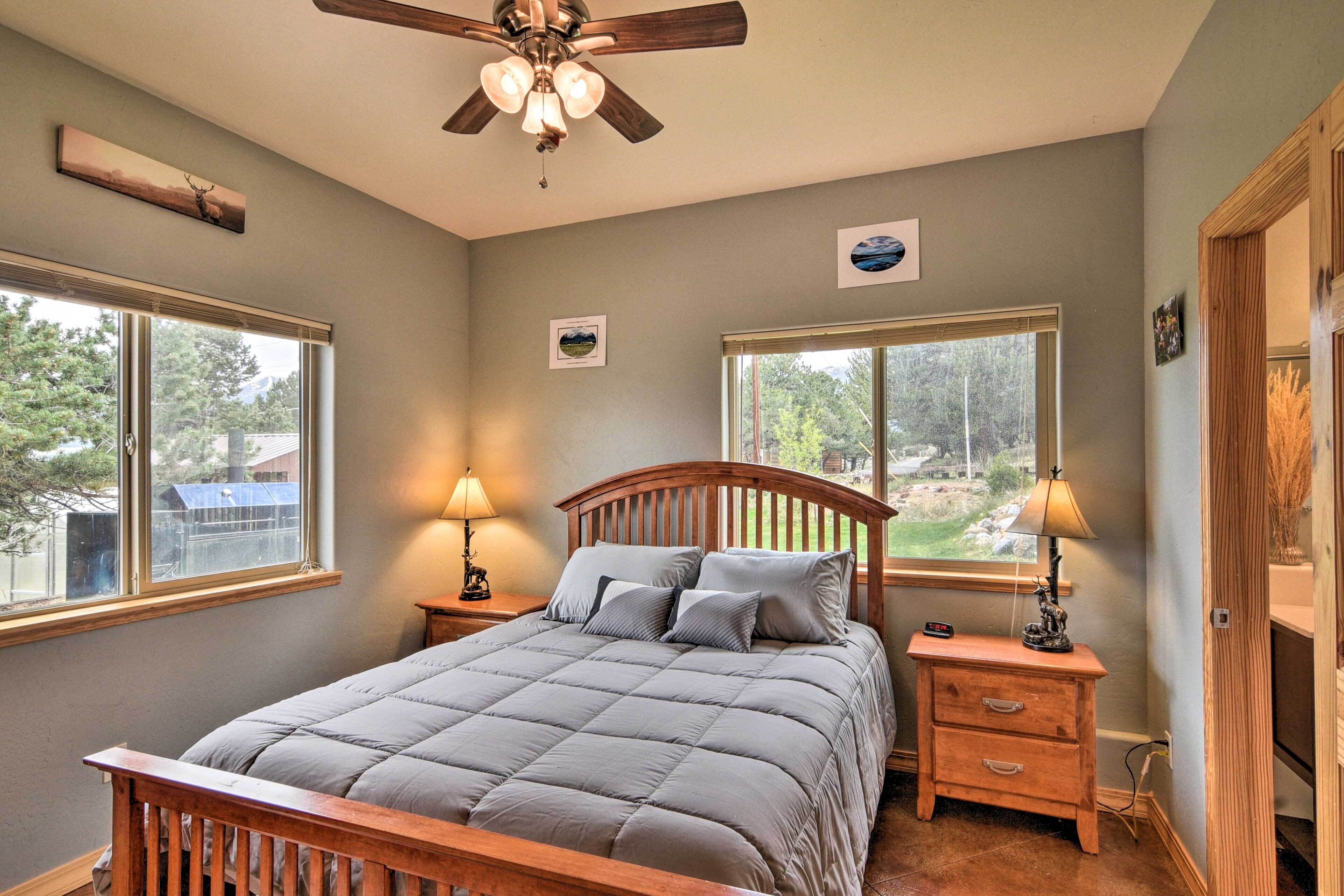 A bedroom with a bed, two bedside tables, a ceiling fan, and two windows.
