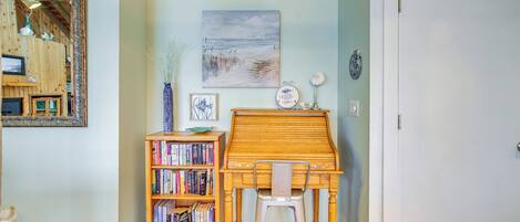 A room with a wooden desk, a bookshelf, a painting, and a door.