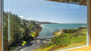 A coastal view from a window, including a beach, rocky shoreline, and greenery. - Idyllic Coastal Haven - Whale Watch in Depoe Bay! (Depoe Bay)