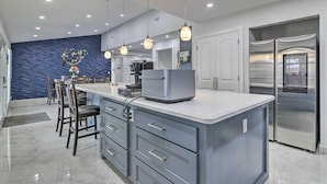 A modern kitchen with a central island, stainless steel appliances, and pendant lighting. - Patio & Grill: Spacious Gem Near Gulf Coast! (Brownsville)