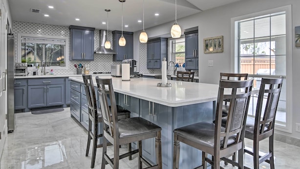 A modern kitchen with grey cabinets, a large island, and pendant lighting. - Patio & Grill: Spacious Gem Near Gulf Coast! (Brownsville)