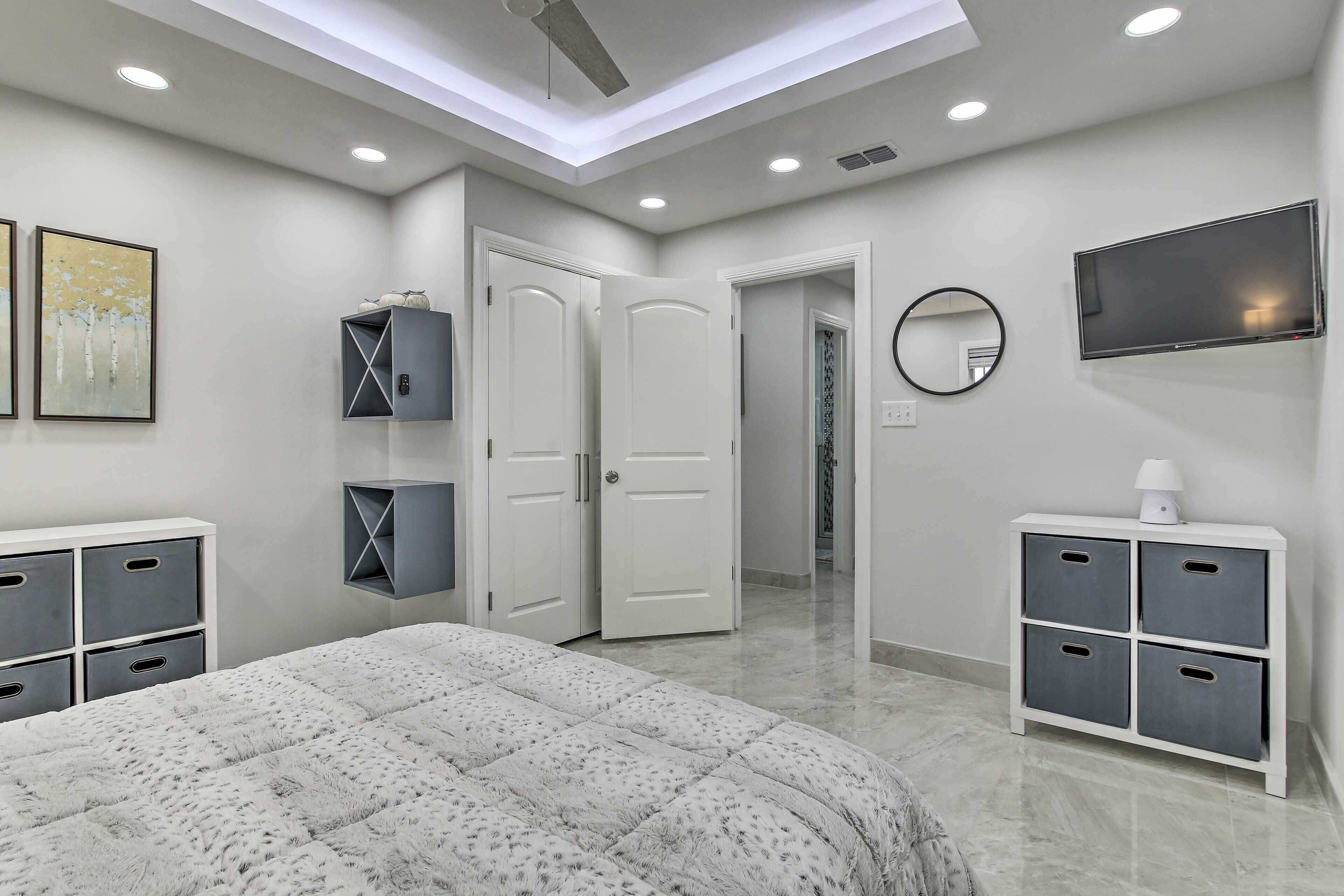 A modern bedroom with a large bed, a TV, and storage units.