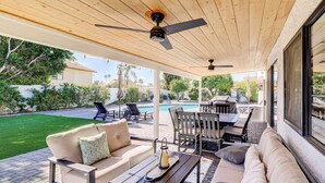 An outdoor patio with a pool, seating area, and ceiling fans.