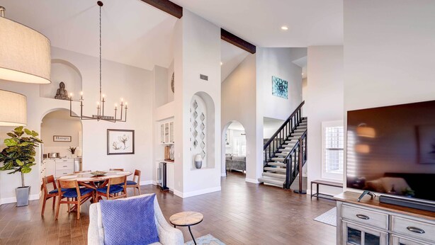 A spacious living room with a dining area, a staircase, and a TV.