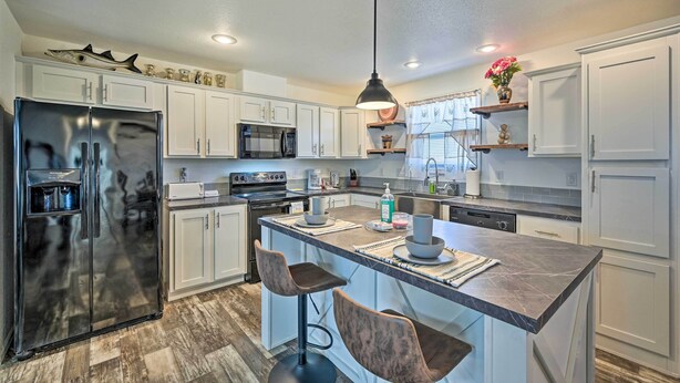 A modern kitchen with white cabinets, stainless steel appliances, and a central island with bar stools.