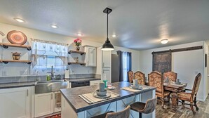 A modern kitchen with a central island, white cabinetry, and a dining area with wooden chairs and a table.