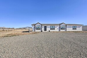 A modern two-story building with a gravel driveway and a clear blue sky. - Modern Prescott Valley Home on 2 Acres! (Prescott Valley)