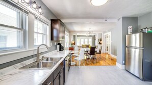 A modern kitchen with a marble countertop, stainless steel appliances, and a dining area with a wooden floor. - Cozy Indiana Getaway Near Washington Park Zoo! (Michigan City)