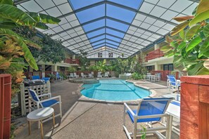 An indoor pool area with a glass ceiling, surrounded by lounge chairs and potted plants. - Coastal Studio w/ Amenities: Walk to Padre Beach! (Corpus Christi)