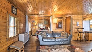 A cozy cabin interior with a leather sofa, a patterned rug, and wooden walls.