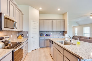 A modern kitchen with granite countertops, stainless steel appliances, and light gray cabinetry. - Spacious Forney Home Rental w/ Game Room! (Forney)