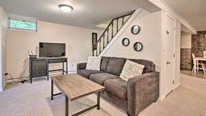 Un salon avec un canapé, une table basse, un téléviseur et un escalier.