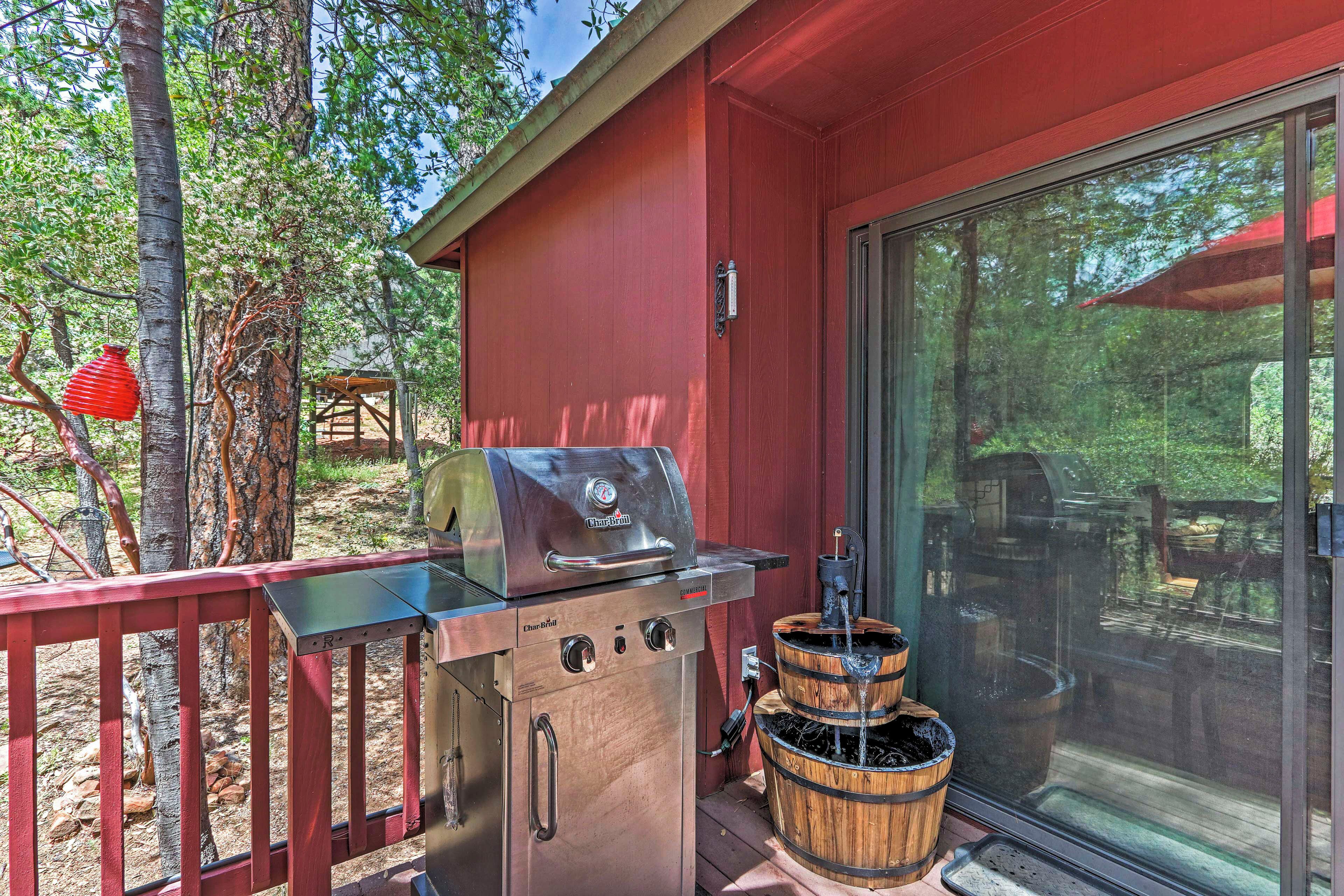 A barbecue grill with a sliding glass door, a wooden deck, and a red railing.