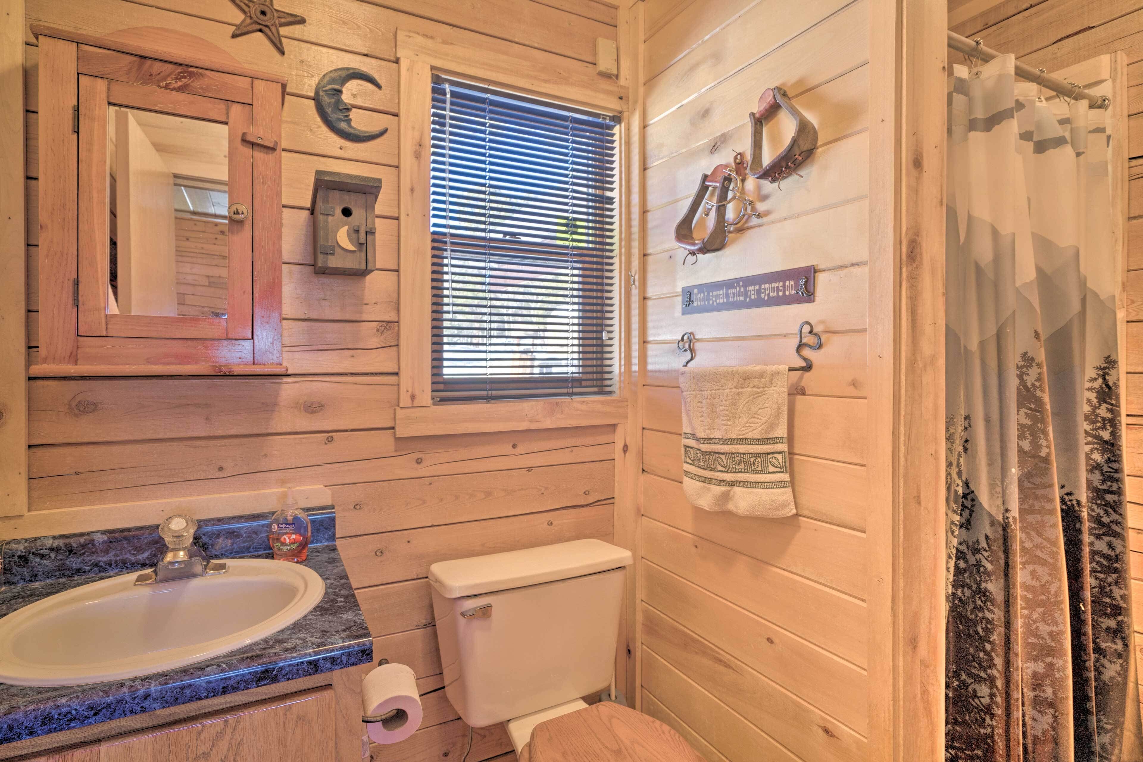 A wooden cabin bathroom with a sink, toilet, and shower curtain.