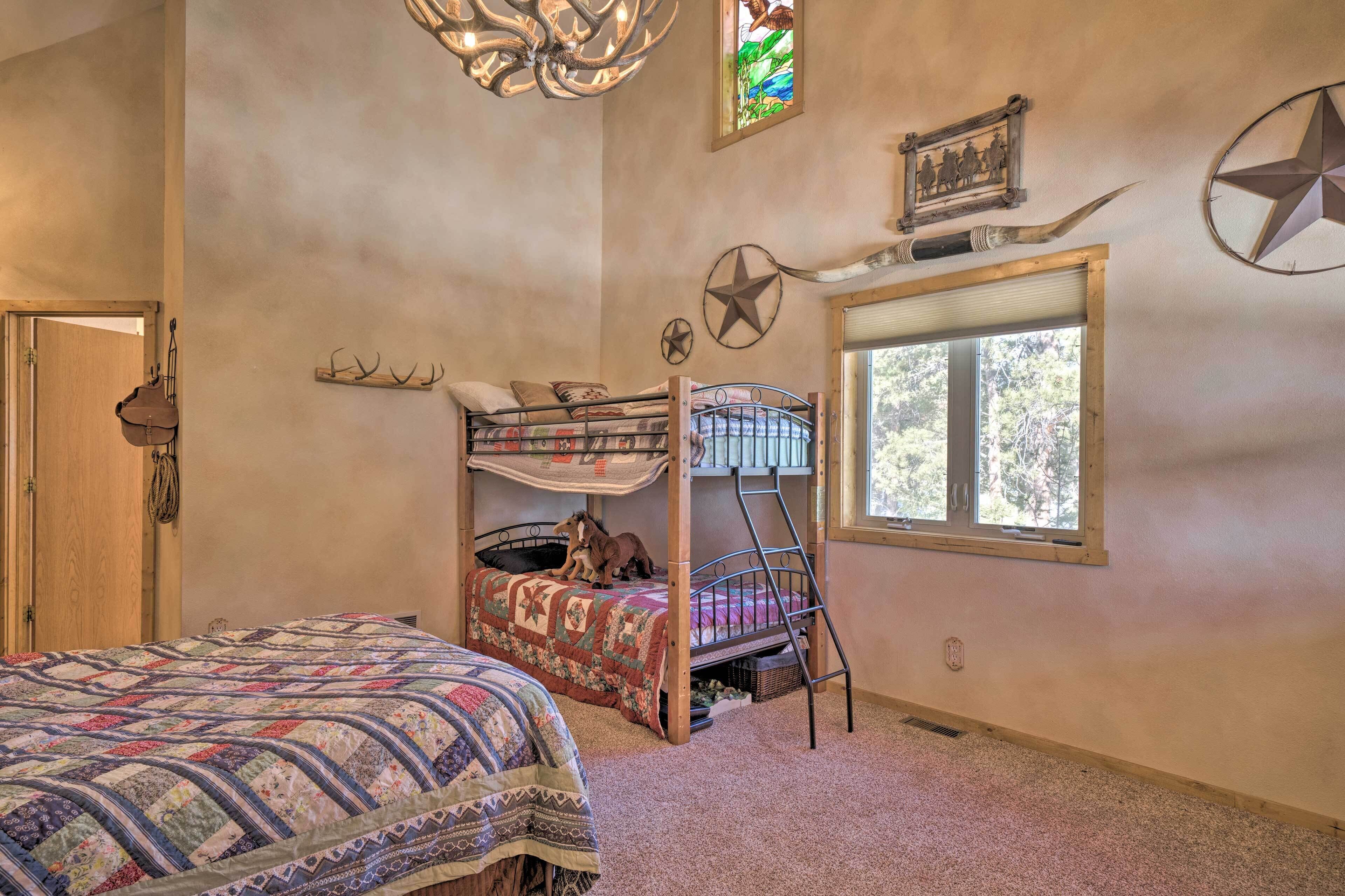 Un dormitorio con una cama litera, una cama grande, una ventana con vistas y una decoración de estrellas en la pared.
