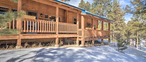 A wooden cabin with a balcony, surrounded by trees and snow.