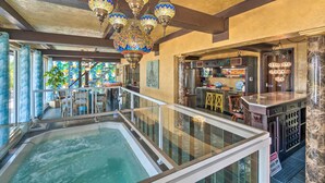 A luxurious interior with a glass-enclosed hot tub, ornate hanging lamps, and a bar area. - Beachfront Home on Gulf of Mexico w/ Indoor Pool (Englewood)
