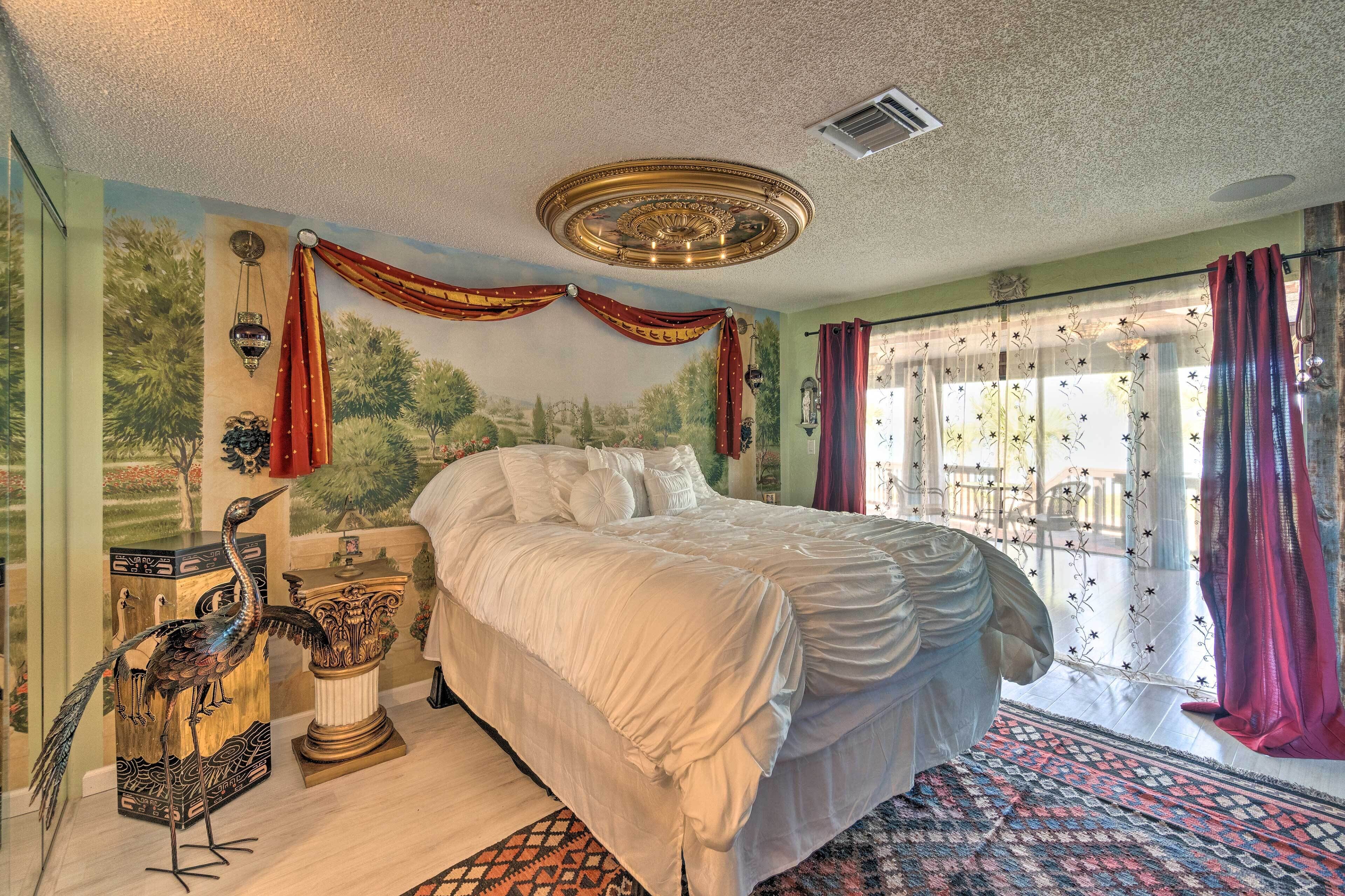Een slaapkamer met een groot bed, een decoratief plafond en uitzicht door het raam.