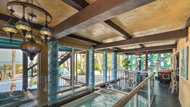 A pool area with a glass railing, a staircase, and a view of the outdoors. - Beachfront Home on Gulf of Mexico w/ Indoor Pool (Englewood)