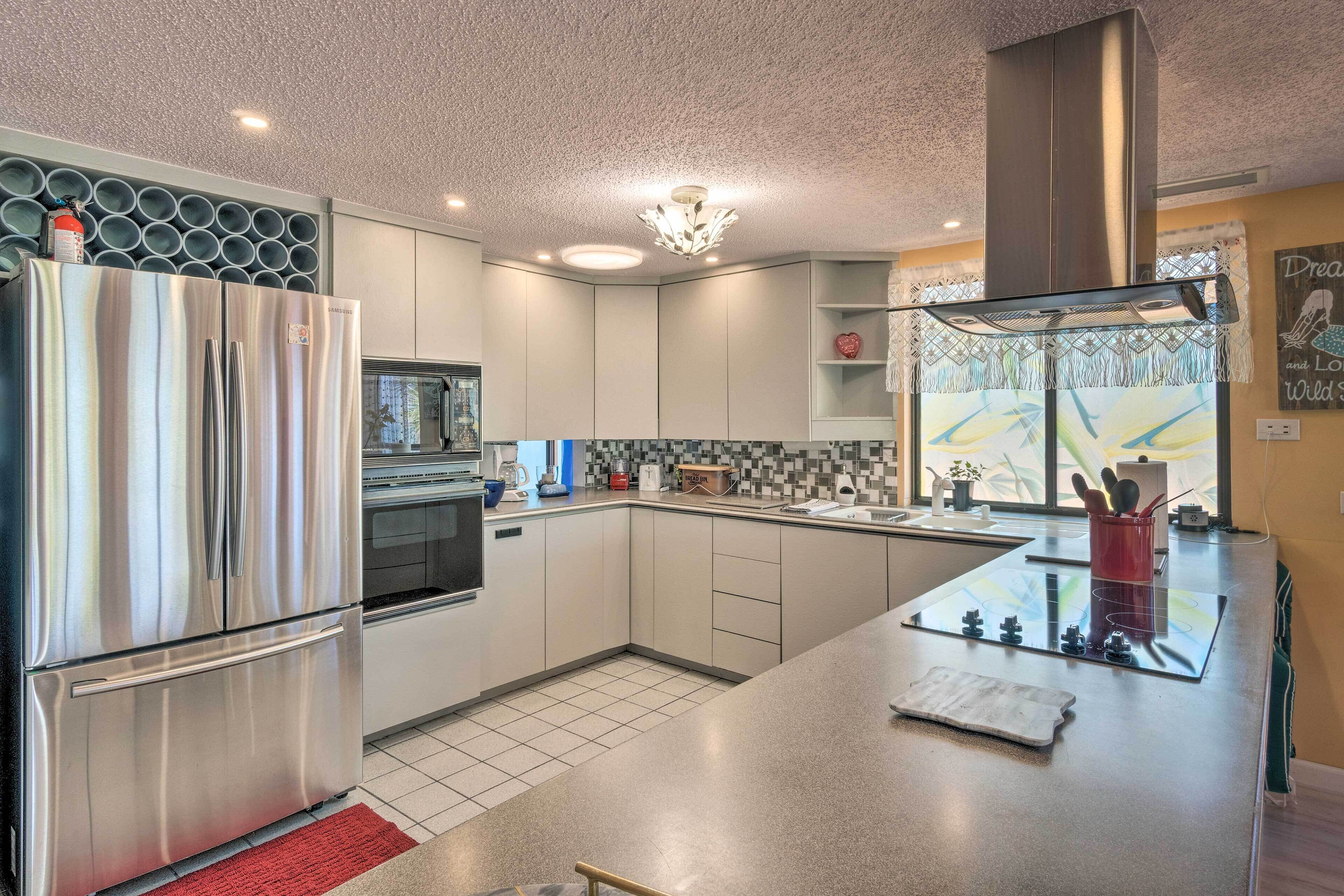 Una cucina moderna con frigorifero in acciaio inossidabile, forno integrato e isola in vetro con lavello.