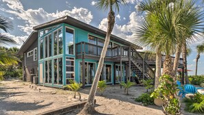 A two-story beachfront house with large windows, a balcony, and a staircase leading to an upper deck. - Beachfront Home on Gulf of Mexico w/ Indoor Pool (Englewood)