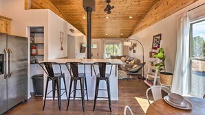 A modern kitchen with a central island, bar stools, and a dining table with plates. - 1 Mi to Hiking: Chic Show Low Escape w/ Fire Pit! (Show Low)