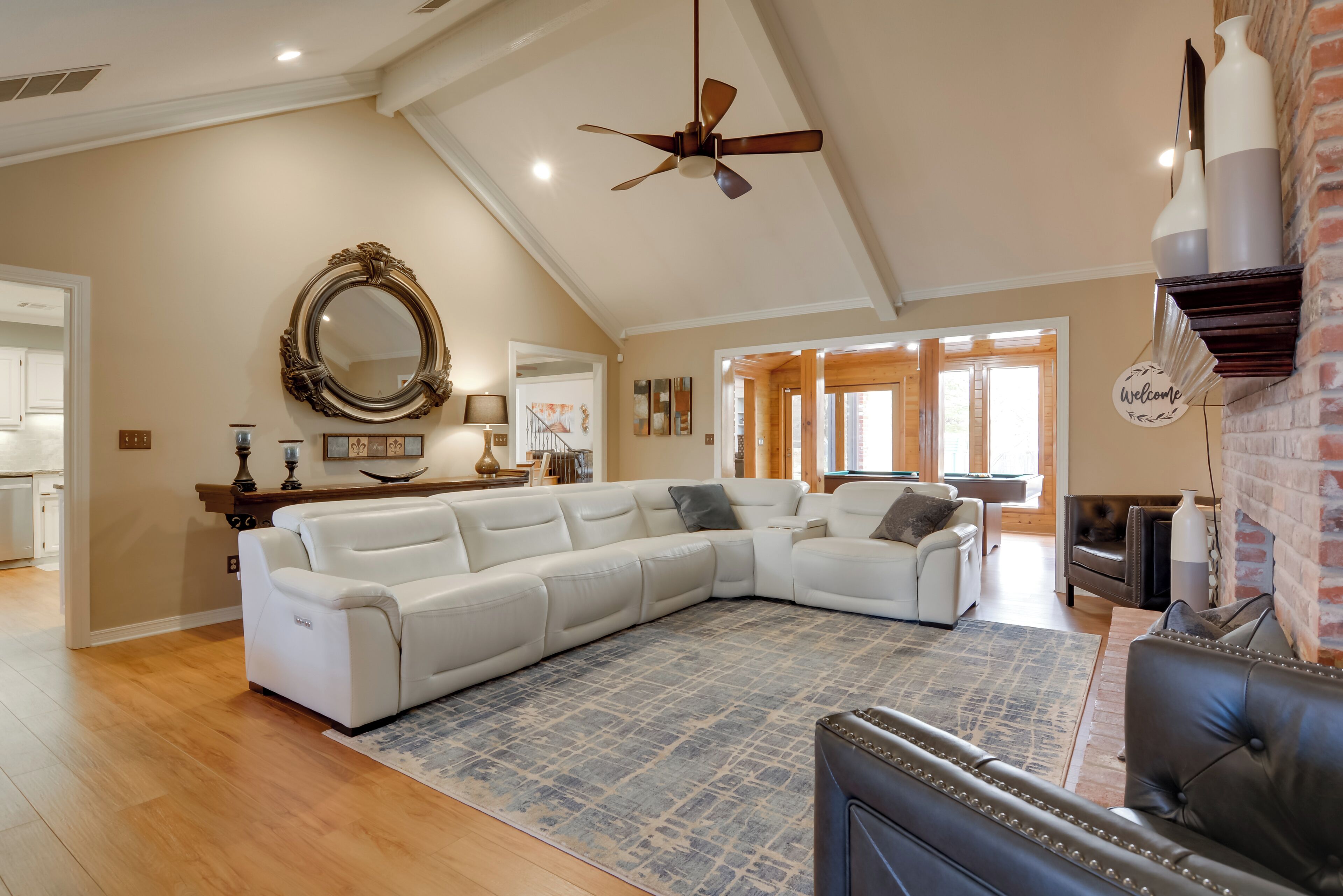 A spacious living room with a large sectional sofa, a fireplace, and a ceiling fan.