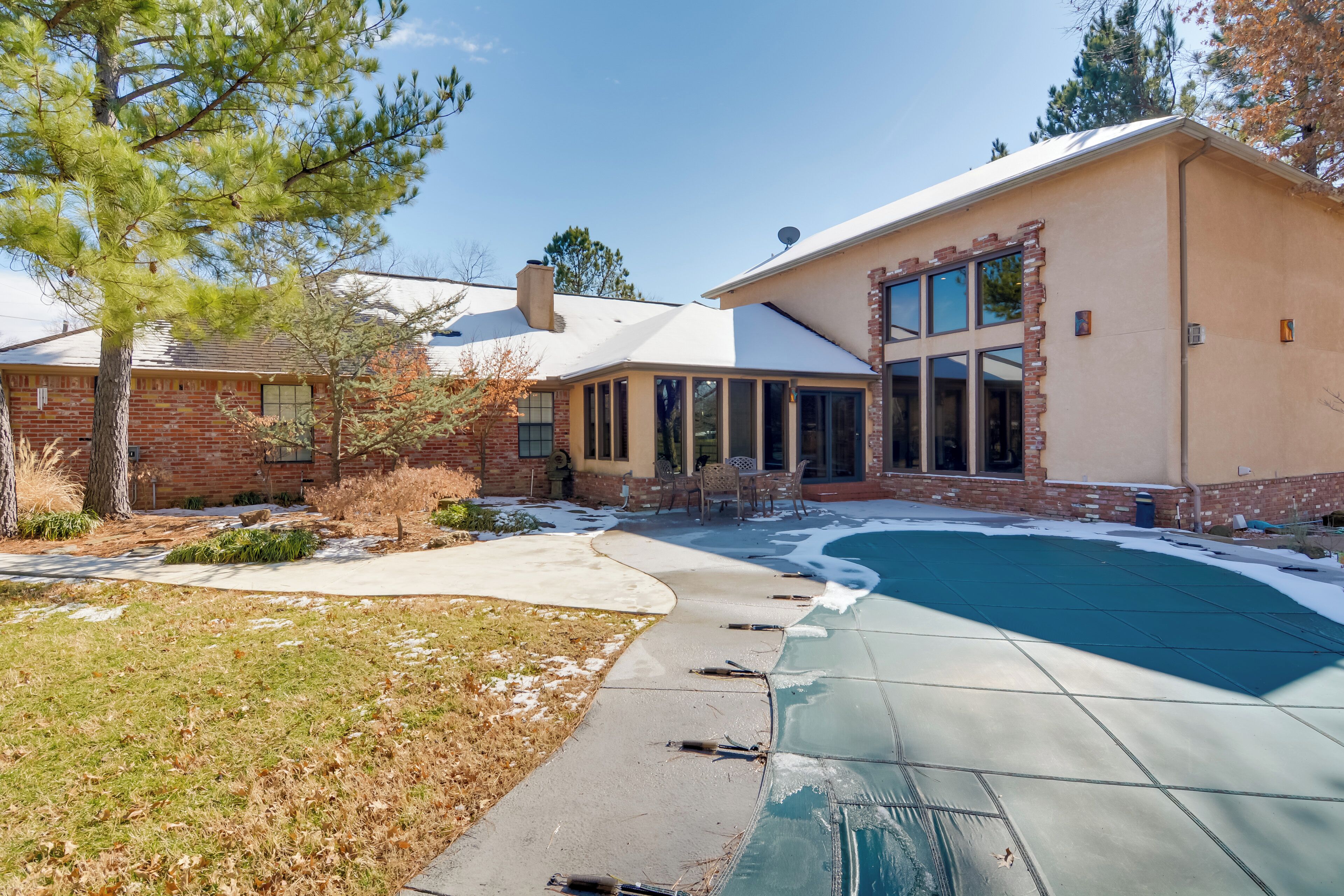 A house with a swimming pool, brick exterior, and large windows.