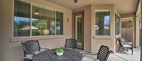 A covered patio with a round table, four chairs, and a ceiling fan.