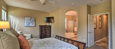 A bedroom with a bed, a dresser, a TV, and a ceiling fan.