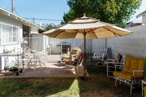 A patio area with outdoor furniture, including chairs and a table, under a large umbrella.