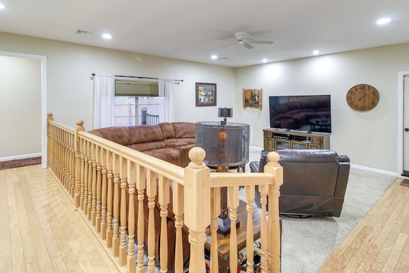 A living room with a brown leather sofa, a brown leather chair, a TV, and a clock on the wall. - Dog-friendly Home on Pinetop Lakes Course! (Pinetop)
